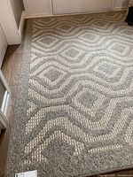 Top-down view of the beige and brown geometric patterned area rug on hardwood floor.