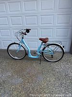 Full side view of light blue Biria cruiser bike parked in front of garage door