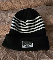 Black and white striped Crooks & Castles toque on blanket surface