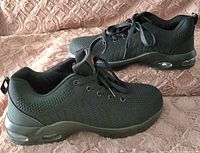 Side angle view of the men's black steel toed work shoe showing mesh upper, laces, and sole with air cushioning.