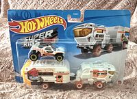 Photo of new sealed Hot Wheels Super Rigs toy set with monster truck and transport rig in original packaging.