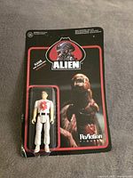 Photo of sealed ALIEN action figure Kane in original ReAction Figures packaging with black and red card backing.