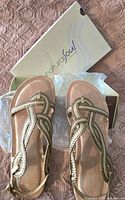 Top view of new braided strap sandals inside Natural Soul box on textured pink surface