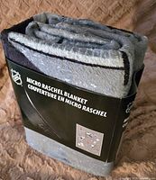Folded NHL micro raschel blanket with packaging label visible showing product name and branding.