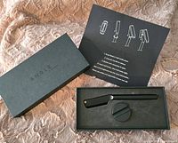 Black box with ANGLE branding and precision barber razor tool with round stand inside, accompanied by an instruction booklet.