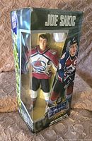 Front and side view of the Joe Sakic 12-inch action figure in sealed Pro Zone packaging showing the figure dressed in Colorado Avalanche uniform.