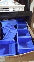 Blue plastic bins inside a cardboard box labeled fragile, showing multiple bins of similar design