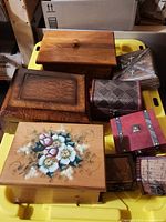 View of six wooden and decorative boxes, including a floral painted box, a carved wooden box, a simple wooden box, a silver embossed metal box, and a red box with metal applique.