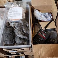 Plastic bin containing multiple steel wool pads, copper foil reel with label, and assorted electrical components in open cardboard boxes.