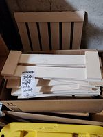 Box filled with stacked white painted wooden slatted panels, large size.