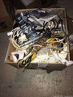 Top-down image of box with various electrical wires, cords, and components including plastic wrap and bubble wrap.