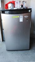 Front view of small Whirlpool fridge showing stainless steel door with brand logo and size label.