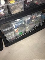 Plastic containers stacked on a shelf containing various electronic and mechanical components, including heat shrink tubing and motors.