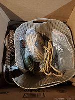 Top view of box including coiled ropes of different types and a light fixture inside a plastic basket.