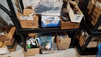 Overview of big shelf with cardboard boxes containing electronic components, motors, and lighting parts.