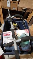 Snow tube in box along with other items visible including chin up bar and rollerblades.