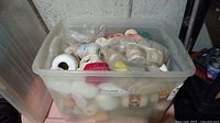 Plastic bin filled with assorted thread and yarn spools, translucent with lid partially visible.