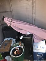 Photo showing the folded garden umbrella surrounded by storage items inside a barn or shed.