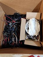 Two cardboard boxes filled with assorted wires and cables in various colors and sizes, including multimeter probes.