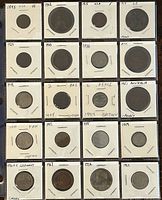 Top view showing 20 assorted world coins in cardboard holders with handwritten dates and countries.