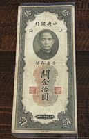 Front side of the 1930 China 10 Customs Gold Units banknote featuring a central portrait, Chinese text, and ornate borders.