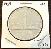 Image of one side of a 1939 Canadian one dollar silver coin showing the Parliament building and inscriptions indicating its denomination and silver content.