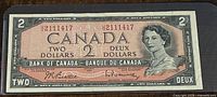 Front side of 1954 Canadian two dollar banknote showing denomination, portrait of Queen Elizabeth II, serial number, and signatures.