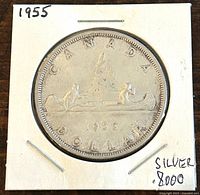 Front side of the 1955 Canadian silver 1 dollar coin showing two men in a canoe and date