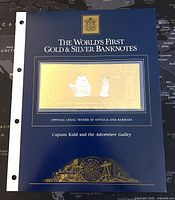 Blue folder cover showing the note as the world's first Gold & Silver banknote, official legal tender of Antigua & Barbuda with depiction of Captain Kidd and the Adventure Galley ships.