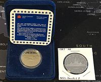 Photo shows the 1987 proof circulating loonie in a blue Royal Canadian Mint presentation case with a descriptive plaque about the coin.