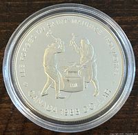 Reverse side showing two blacksmiths hammering on an anvil with date and denomination.