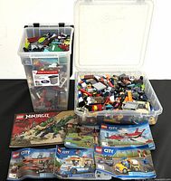 Two large plastic containers filled with assorted LEGO pieces and several instruction manuals laid out in front including LEGO Ninjago, Disney, and City.