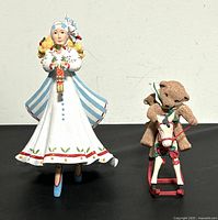 Front view of the Clara Nutcracker figure and teddy bear rocking horse on a black surface against a white wall.