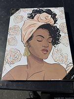 Front view of the art print still in packaging, showing the illustration of the woman with roses and head wrap.
