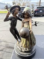 Front view of bronze statue depicting a boy and a girl holding a ball, displaying overall form and patina.