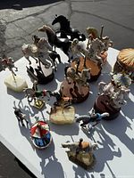 Overhead view of 18 horse and carousel figurines arranged on a white surface, showing variation in sizes and colors.