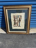Framed Egyptian papyrus art piece with traditional figures and hieroglyphics