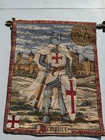 Needle stitch tapestry showing a Knight Templar in armor with red crosses, castle background, bordered in red