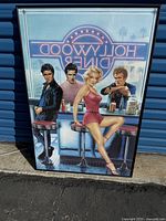 Framed Hollywood Diner poster showing Marilyn Monroe, Elvis Presley, James Dean, and another male figure at a diner counter with a neon sign.