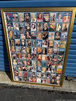 Photo of first framed panel showing uncut original Marilyn Monroe trading cards in various iconic images and poses, with a gold-toned wooden frame, leaning against a blue wall outdoors.
