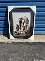Framed black and white photo of Hollow Horn Bear against blue metal background, showing photo and frame with protective corners.