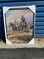 Framed print showing two Native Indians on horses with natural rocky landscape and cloudy sky.