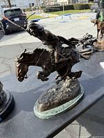 Full view of bronze statue showing rider and horse in action on marble base
