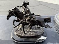 Side view of two bronze horsemen on marble base