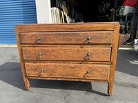 Front view of the oak rolling cabinet showing three drawers with metal handles.