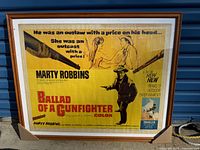 Framed vintage movie poster 'Ballad of a Gunfighter' with promotional text and artwork, showing condition and packaging corners