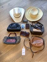 Wide shot of all items on wooden floor showing full lot contents including two hats, multiple purses, wallets and a coin purse.