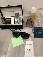 Wide shot showing Guerlain set in case, three glass bottles, sunglasses, cleaning cloth and pouch
