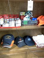 Photo of wooden shelf with Canon printer ink cartridges, baseball caps, books, dolphin figurine, and Samsung box.
