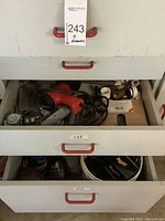 Four drawers filled with assorted garage items including heat tool, flashlight, screws, nails, plumbing parts, car care supplies.